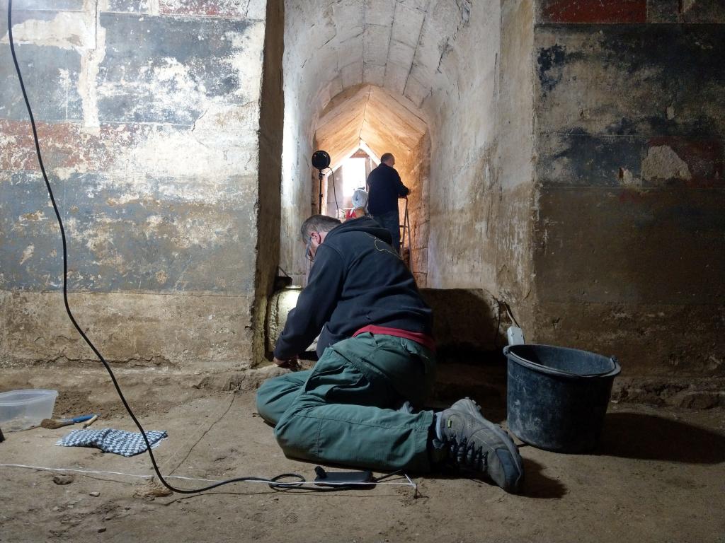 Tomasz Bochnak w czasie pracy wewnątrz komory grobowej. Na ścianach widoczne są barwne polichromie. Fot. W. Rzepka